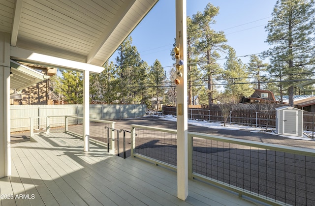 deck with a storage shed, an outbuilding, and a fenced backyard