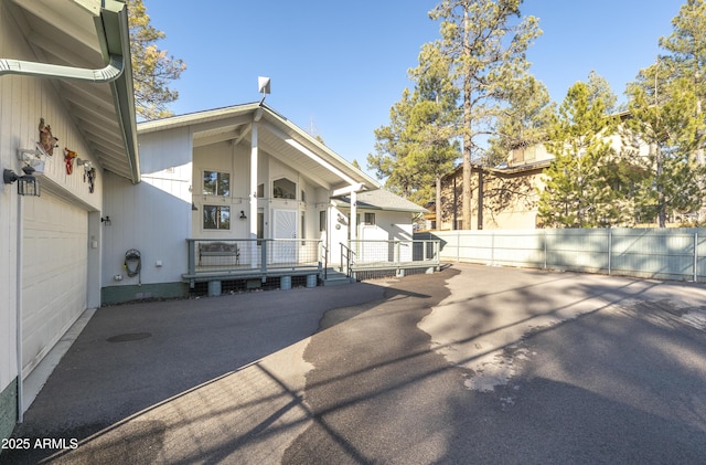 view of side of property featuring an attached garage, driveway, and fence