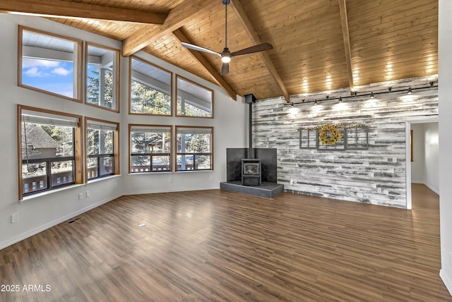 unfurnished living room with beam ceiling, wood ceiling, a wood stove, and wood finished floors