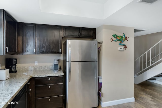 kitchen featuring dark brown cabinetry, stainless steel fridge, light stone counters, and light hardwood / wood-style flooring