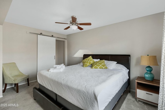 bedroom with light colored carpet, a barn door, and ceiling fan