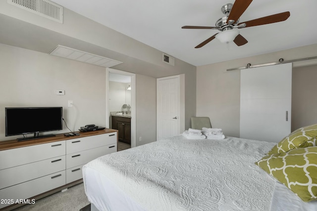 carpeted bedroom with ensuite bathroom, a barn door, and ceiling fan