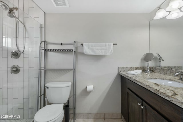 bathroom featuring tile patterned flooring, vanity, a tile shower, and toilet