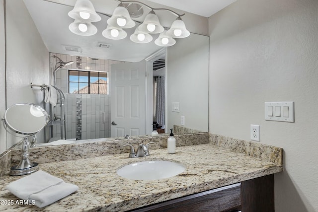 bathroom featuring tiled shower and vanity