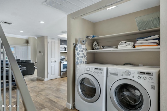 clothes washing area with light hardwood / wood-style flooring and washing machine and dryer