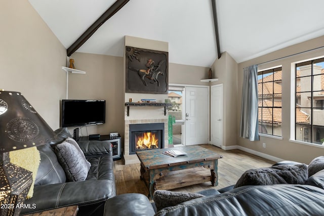 living room featuring beam ceiling, high vaulted ceiling, light wood-type flooring, and a fireplace