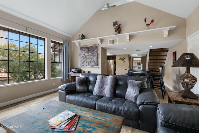 living room with high vaulted ceiling and light wood-type flooring