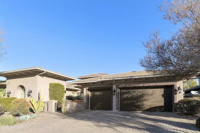 view of side of home with an attached garage, decorative driveway, and stucco siding