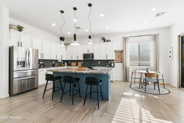 1492 W Bruce Ave, Gilbert, AZ 85233 - kitchen with appliances with stainless steel finishes, decorative backsplash, a breakfast bar, a kitchen island, and recessed lighting