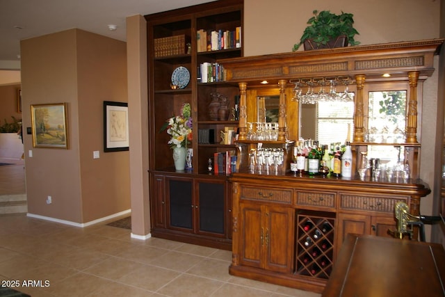 bar with light tile patterned floors, a dry bar, and baseboards