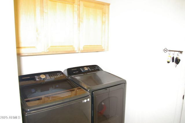 washroom featuring cabinet space and washer and clothes dryer