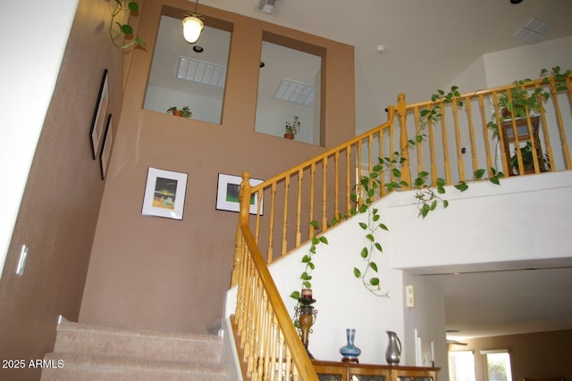 stairway featuring visible vents and a towering ceiling