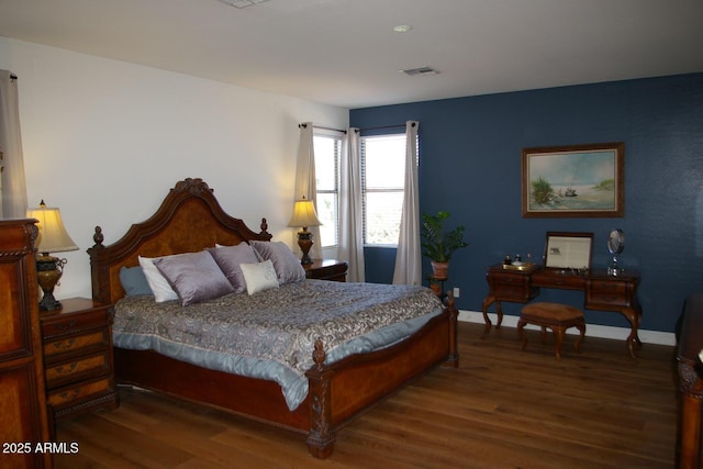 bedroom featuring visible vents, baseboards, and wood finished floors