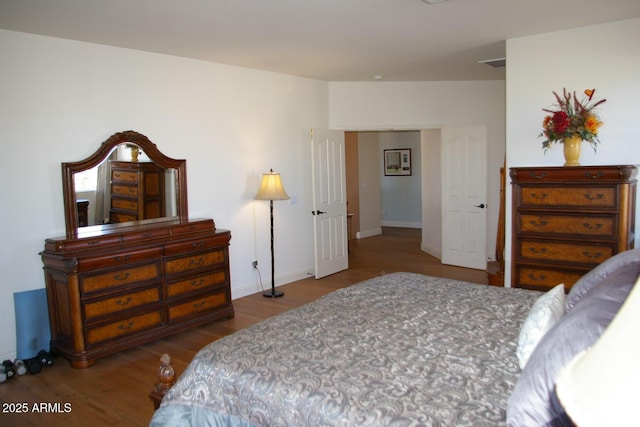 bedroom with visible vents, baseboards, and wood finished floors