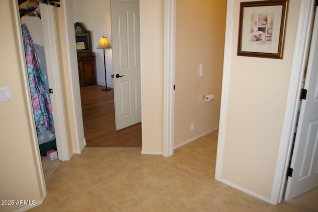 hallway featuring baseboards and light tile patterned floors