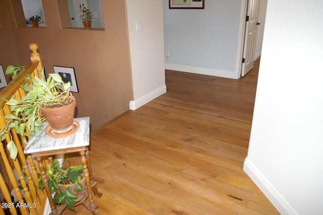 corridor featuring baseboards and wood finished floors