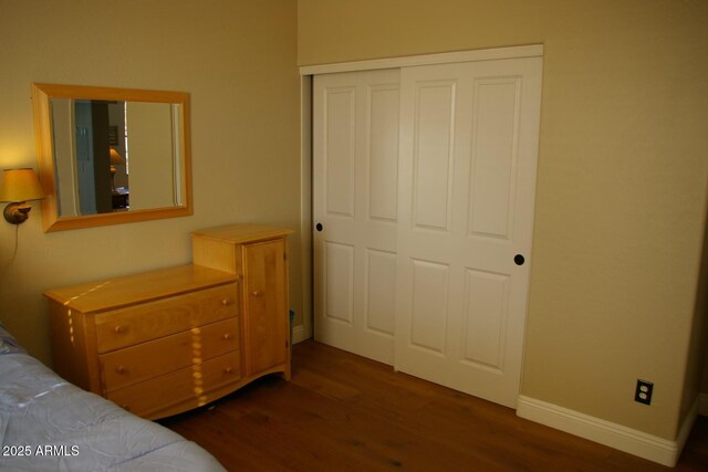 bedroom with a closet, baseboards, and wood finished floors