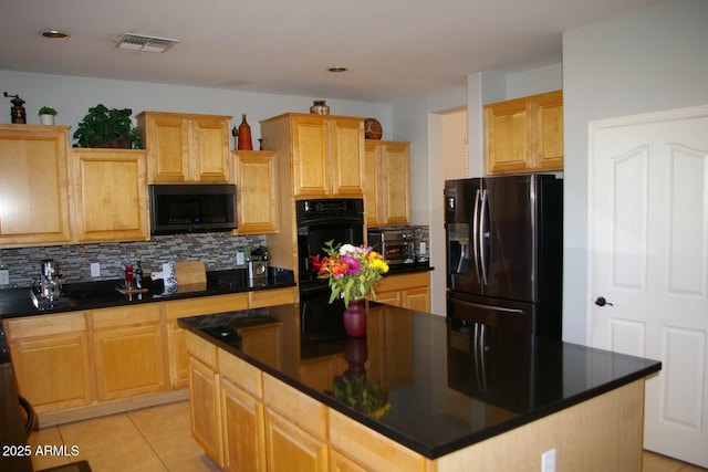 kitchen featuring black appliances, dark countertops, and visible vents