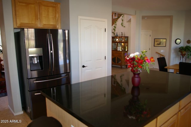 kitchen featuring dark countertops, light tile patterned flooring, and black fridge with ice dispenser