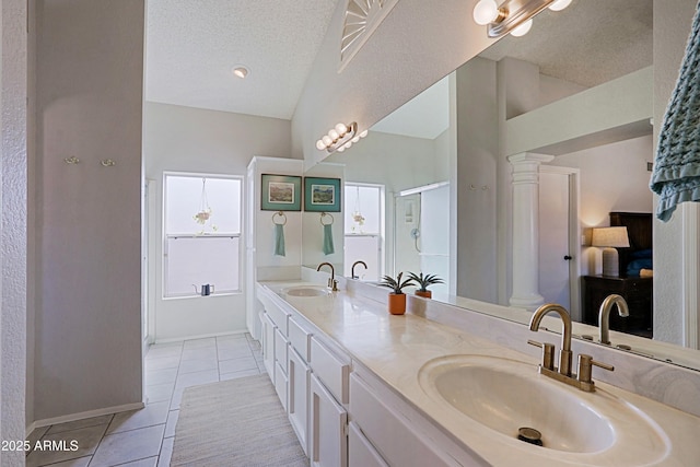 full bathroom with tile patterned floors, double vanity, a sink, and decorative columns