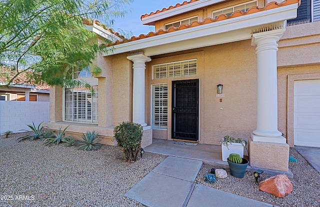 property entrance with a tile roof, fence, and stucco siding