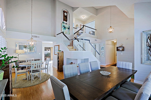 dining area with light wood finished floors, visible vents, baseboards, stairway, and a notable chandelier