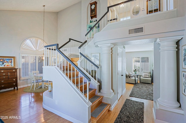 stairs featuring a towering ceiling, decorative columns, and visible vents