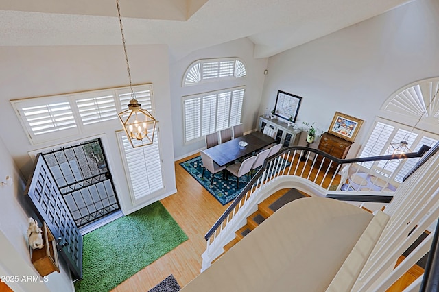 foyer featuring baseboards, wood finished floors, a towering ceiling, and an inviting chandelier