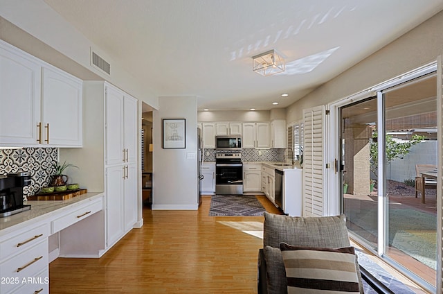 kitchen featuring a sink, white cabinets, light countertops, appliances with stainless steel finishes, and light wood finished floors