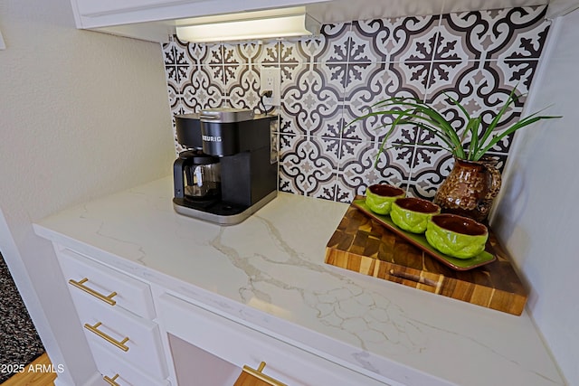 interior details featuring white cabinetry and light stone counters