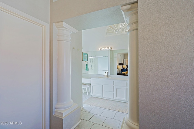 bathroom featuring a textured wall, vanity, ornate columns, and tile patterned floors