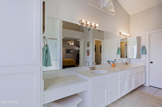 ensuite bathroom featuring ceiling fan, double vanity, a sink, and connected bathroom