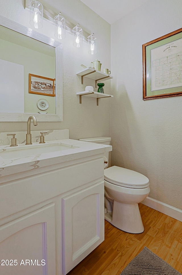 bathroom with wood finished floors, vanity, toilet, and baseboards