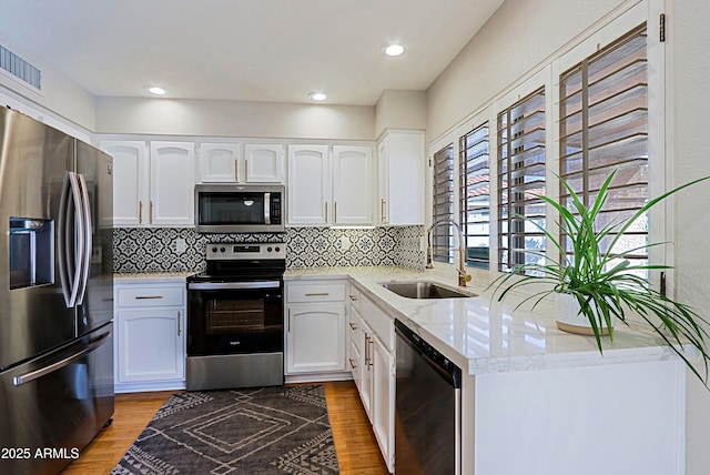 kitchen with white cabinets, stainless steel appliances, a sink, and wood finished floors