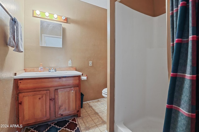 bathroom with tile patterned flooring, walk in shower, vanity, and toilet