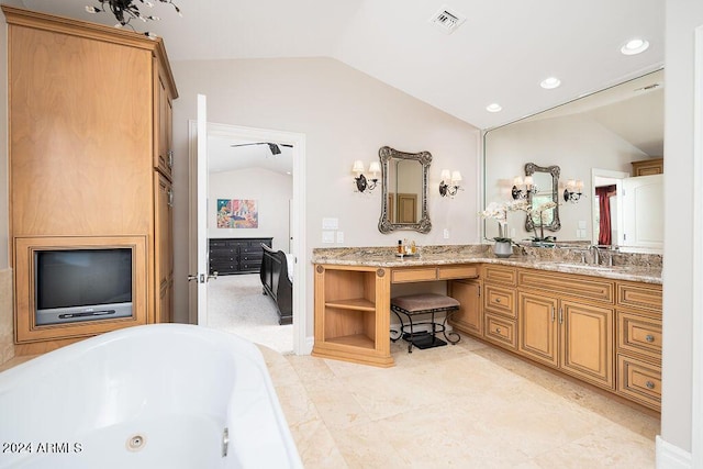 bathroom featuring ceiling fan, vanity, lofted ceiling, and a bathing tub