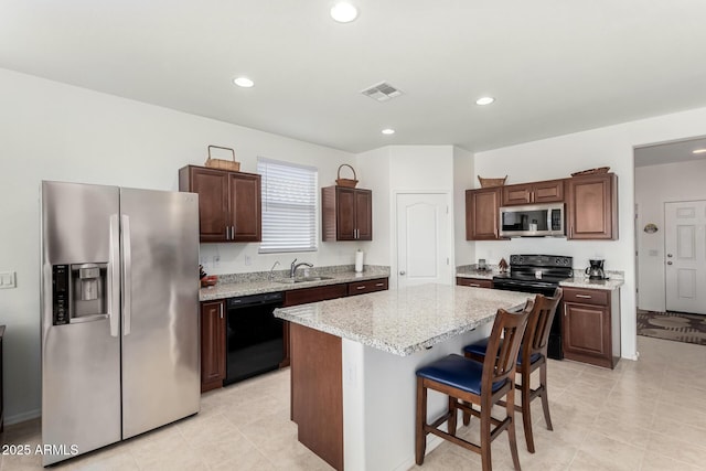 kitchen featuring sink, a kitchen bar, a center island, dark brown cabinetry, and black appliances