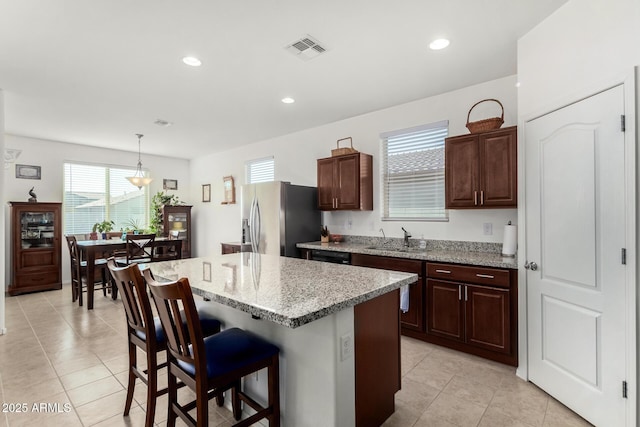 kitchen featuring a breakfast bar, sink, a center island, stainless steel fridge with ice dispenser, and pendant lighting