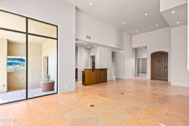 unfurnished living room featuring a towering ceiling