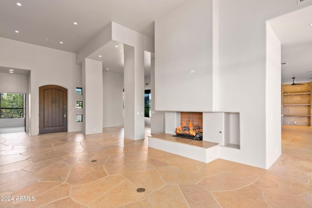 tiled foyer featuring a towering ceiling and a multi sided fireplace