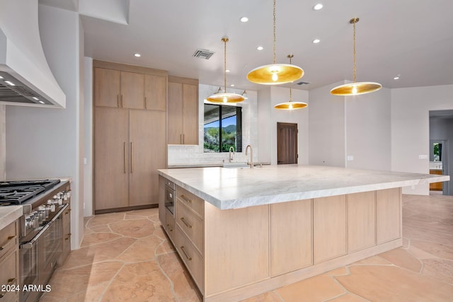 kitchen featuring decorative light fixtures, light tile flooring, light brown cabinets, an island with sink, and premium range hood