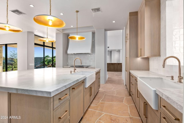 kitchen featuring hanging light fixtures, tasteful backsplash, sink, and a kitchen island with sink