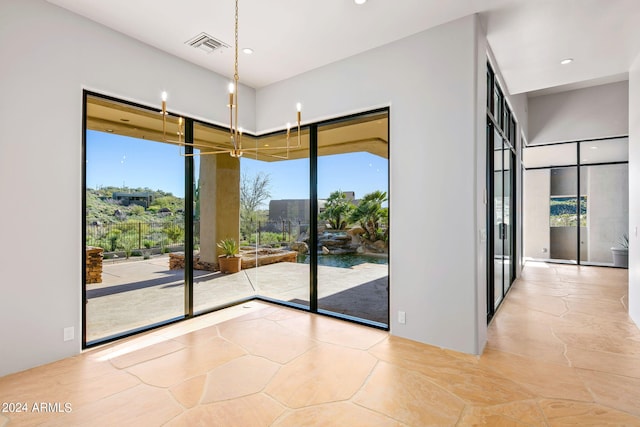 empty room featuring an inviting chandelier and light tile floors