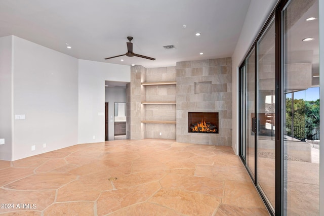 unfurnished living room with tile walls, a fireplace, and ceiling fan