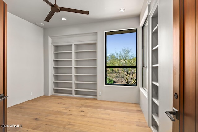 unfurnished room featuring built in features, ceiling fan, and light wood-type flooring