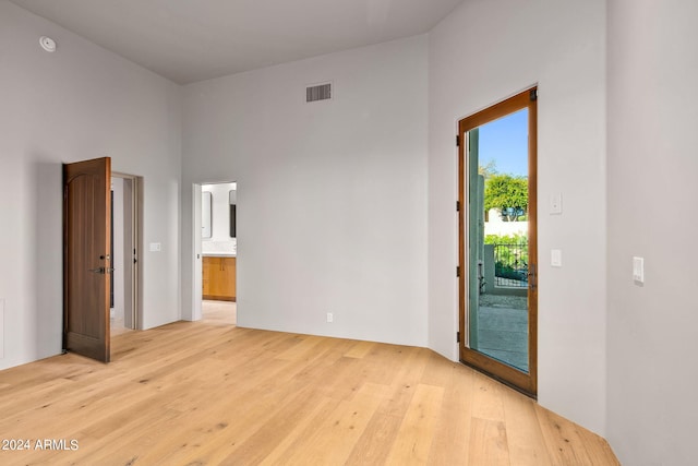 unfurnished bedroom with light hardwood / wood-style flooring, access to exterior, a high ceiling, and ensuite bathroom