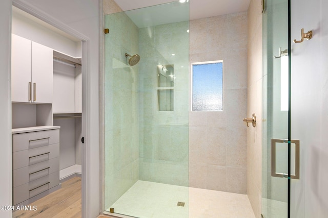 bathroom with a shower with shower door and hardwood / wood-style flooring