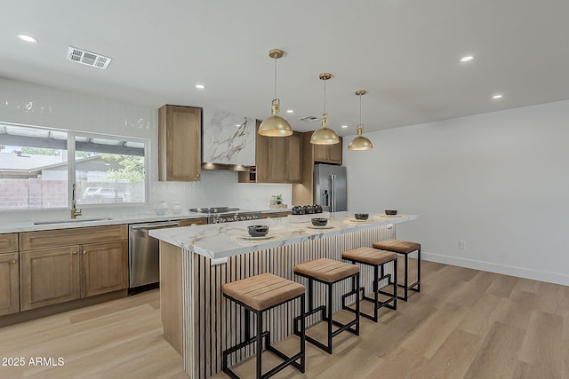 5028 W Shangri La Rd, Glendale, AZ 85304 - kitchen featuring stainless steel appliances, light wood finished floors, a breakfast bar, a kitchen island, and recessed lighting
