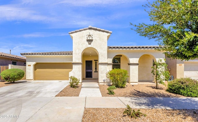 mediterranean / spanish home with an attached garage, concrete driveway, stucco siding, and a tile roof
