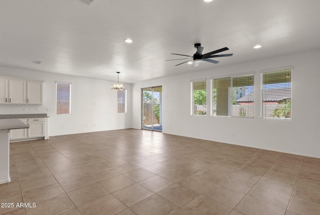 unfurnished living room with ceiling fan with notable chandelier, light tile patterned flooring, and recessed lighting